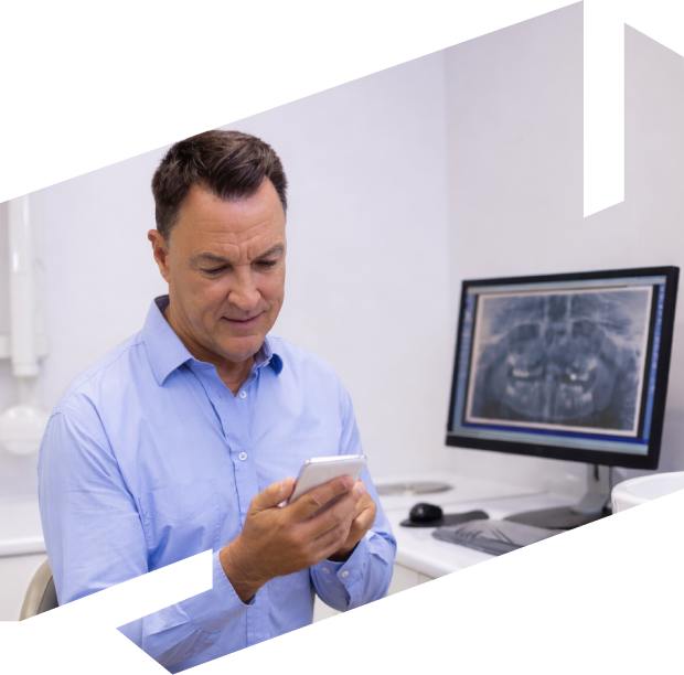 Doctor looking at phone with medical scans on computer